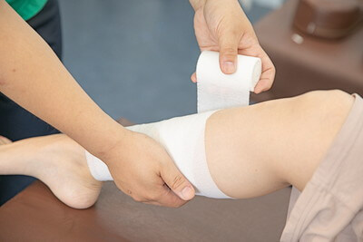 ふくらはぎのケガに対し包帯を使って応急処置をしている時の写真