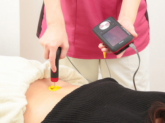 ハイボルト治療器で腰の炎症を取り除いている時の施術写真。