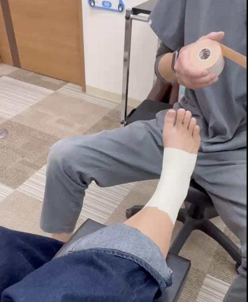 おりおスポーツ接骨院の先生が足関節の捻挫のケガに対して、テーピングによる固定処置をしている時の写真。