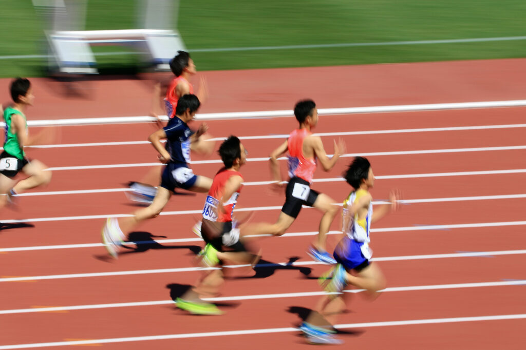 陸上競技の短距離走を学生が走っている時の写真