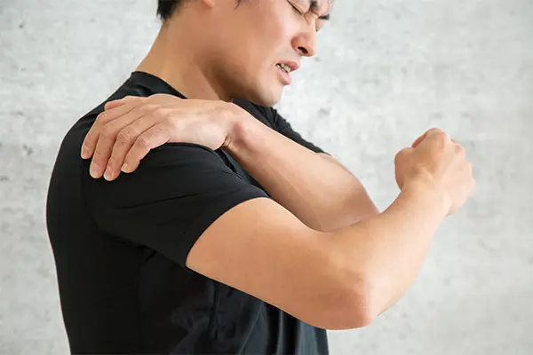 肩の痛みが取れずに困っている時の男性の写真。
