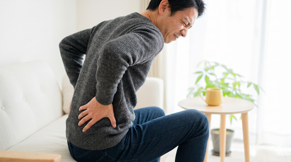 腰の痛みを抱えている男性の写真。